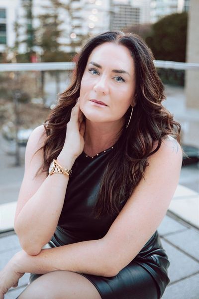 Woman with long brown hair and black dress posing.