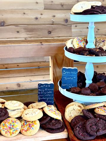 Assorted cookies and brownies displayed on wooden shelves and a blue tiered stand.