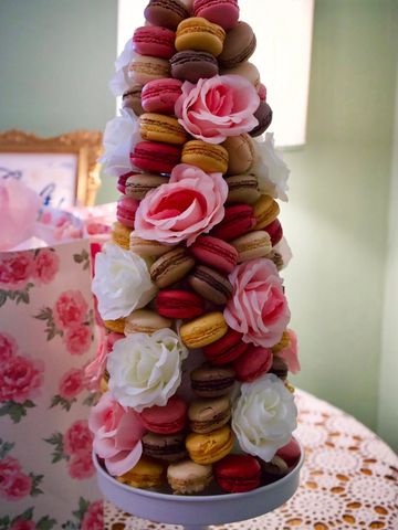 A tower of colorful macarons decorated with pink and white roses.