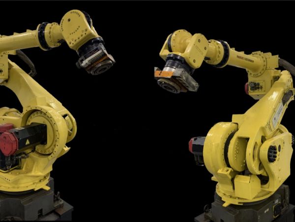 Two yellow industrial robotic arms against a black background.