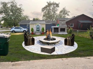 Cozy backyard fire pit area with chairs and grill.