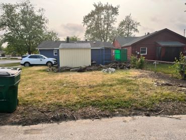 Backyard with a green trash bin and two houses.