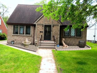 Brick house with garden sculptures and green lawn.
