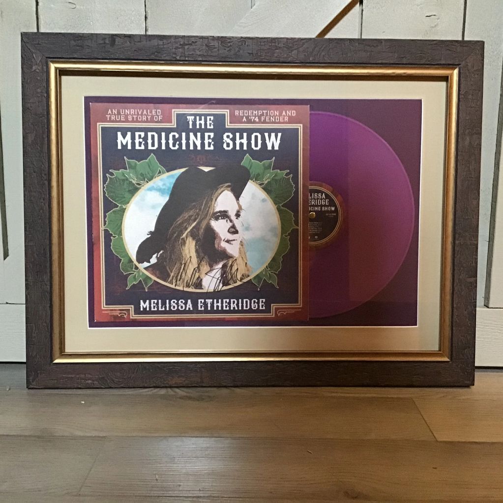 Framed cover art of Melissa Etheridge's album "The Medicine Show" alongside a purple vinyl record.