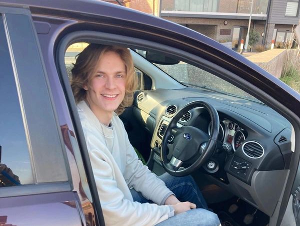 Young man sitting and smiling inside a car.