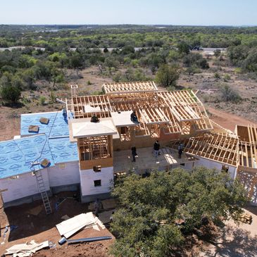 A large house under construction with workers on the wooden framework.