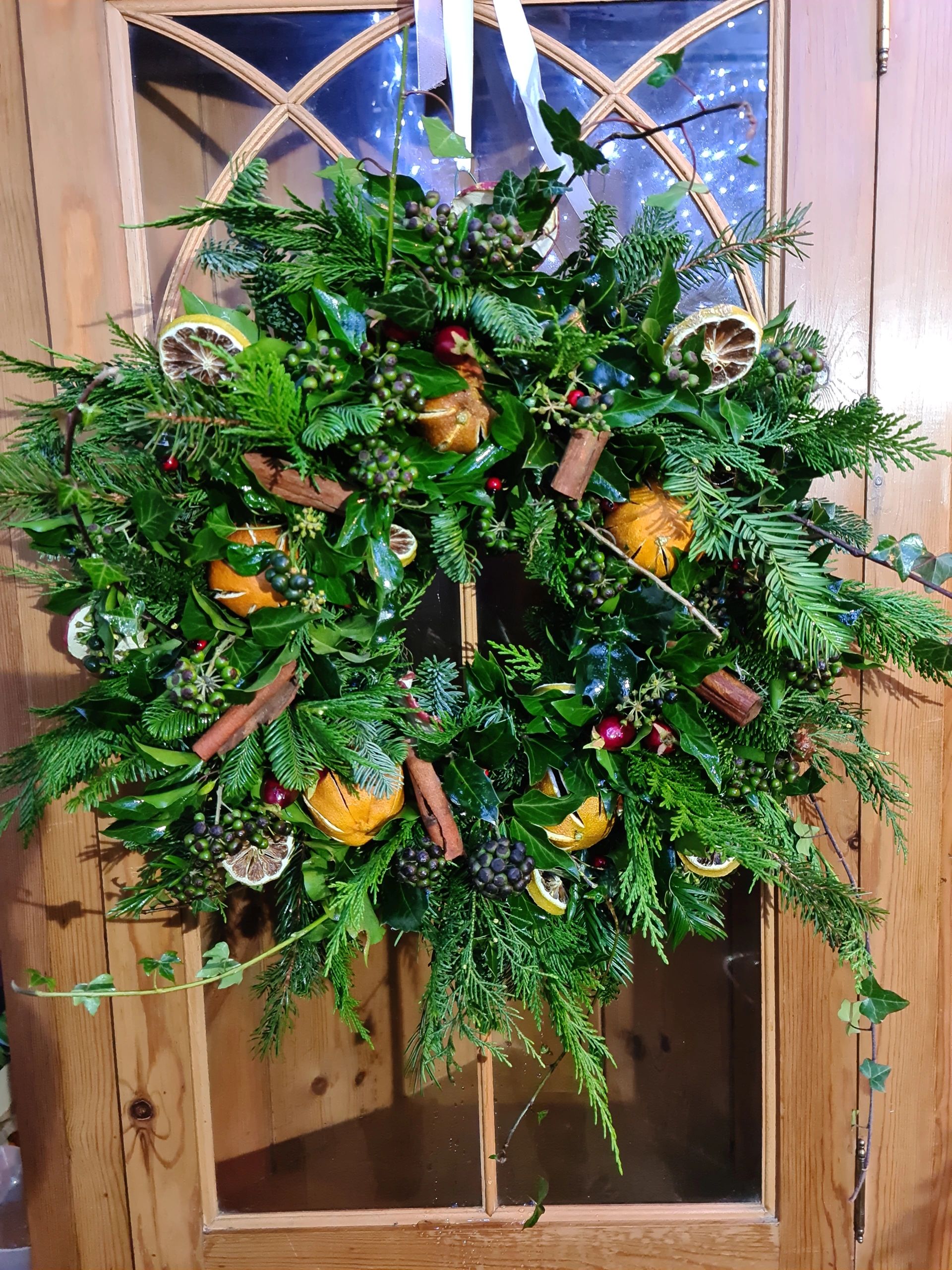 Luxury fresh foliage Christmas wreath whole oranges lime slices and ivy berries, wild and natural