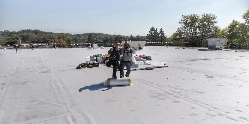 Drone photo of two roofers working on a commercial roofing project in Eden Prairie