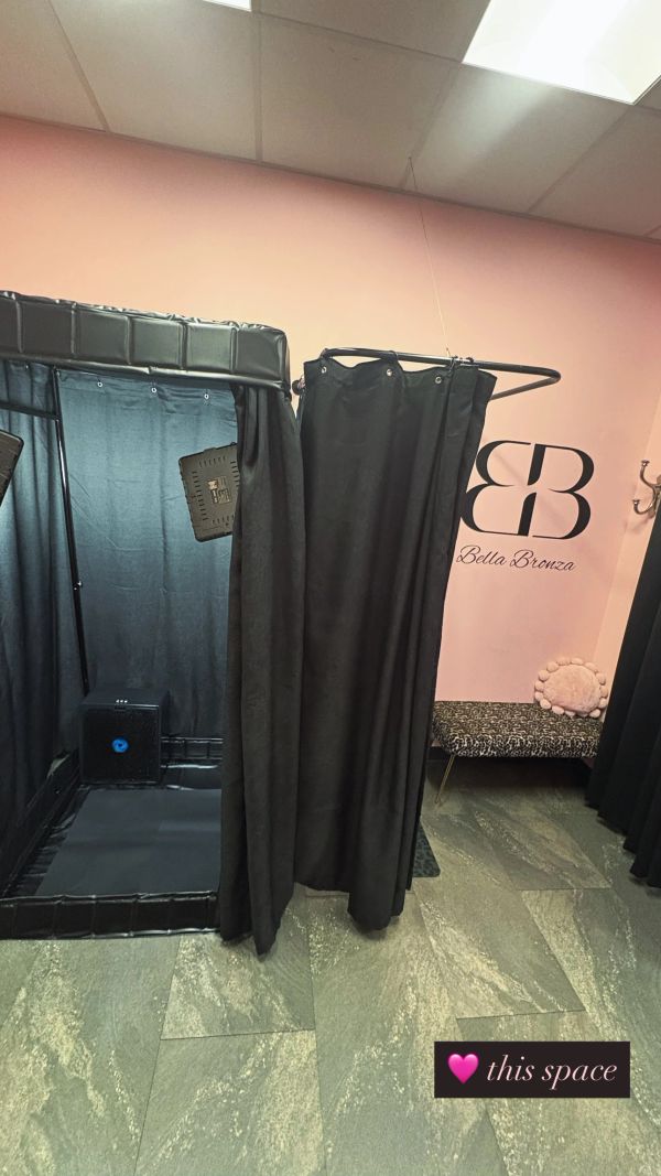 Tanning booth with black curtains and Bella Bronza logo.