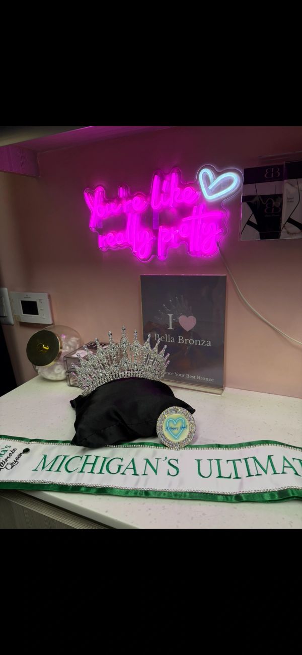Pageant crown, sash, and neon sign with heart.