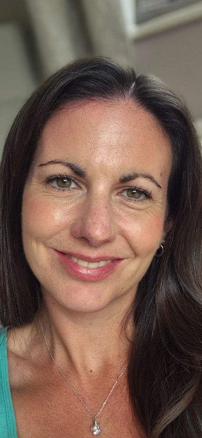 Close-up portrait of a smiling woman with brown hair and green eyes.