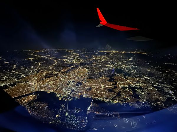 View out airplane window in flight night time view of Manhattan, New York lit up