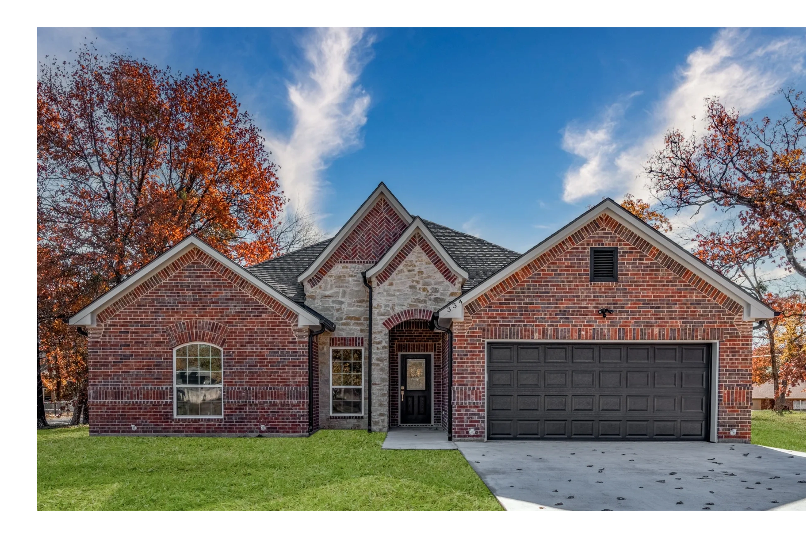 A bricked house with a black door and black garage