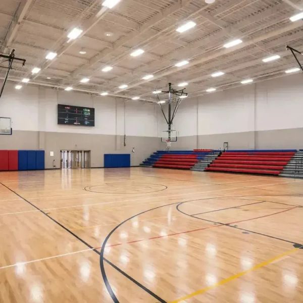 Empty indoor basketball court with red bleachers.