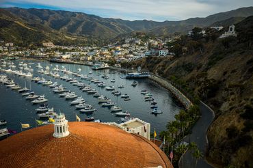 Aerial view of top of the famous Avalon Casino with boats parked and mountain view.