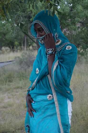 Desert woman with blue scarf wrapped in front of face.