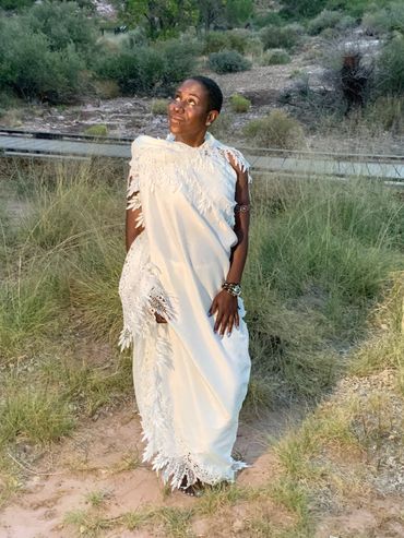 Desert woman (Queen) in white looking towards sky.