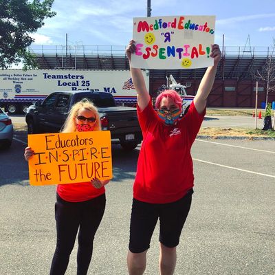 Sara Dion and a fellow teacher, both wearing red t-shirts, holding signs with pro-educator slogans.