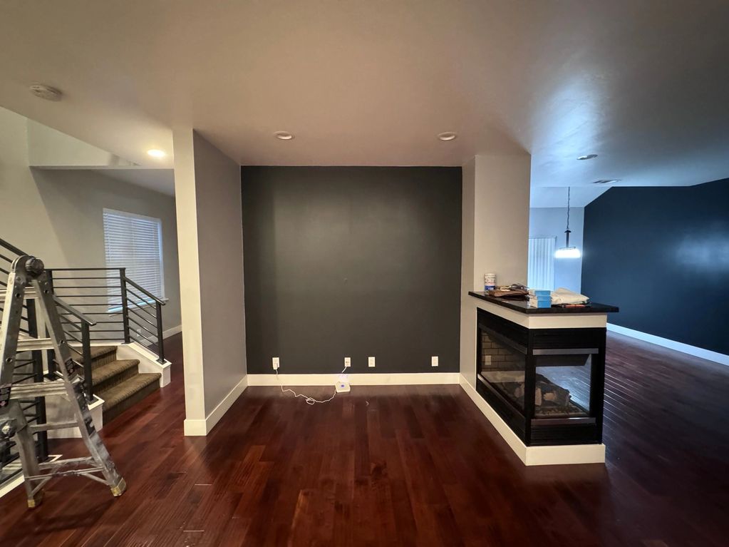 Empty modern living space with dark accent wall and ladder.