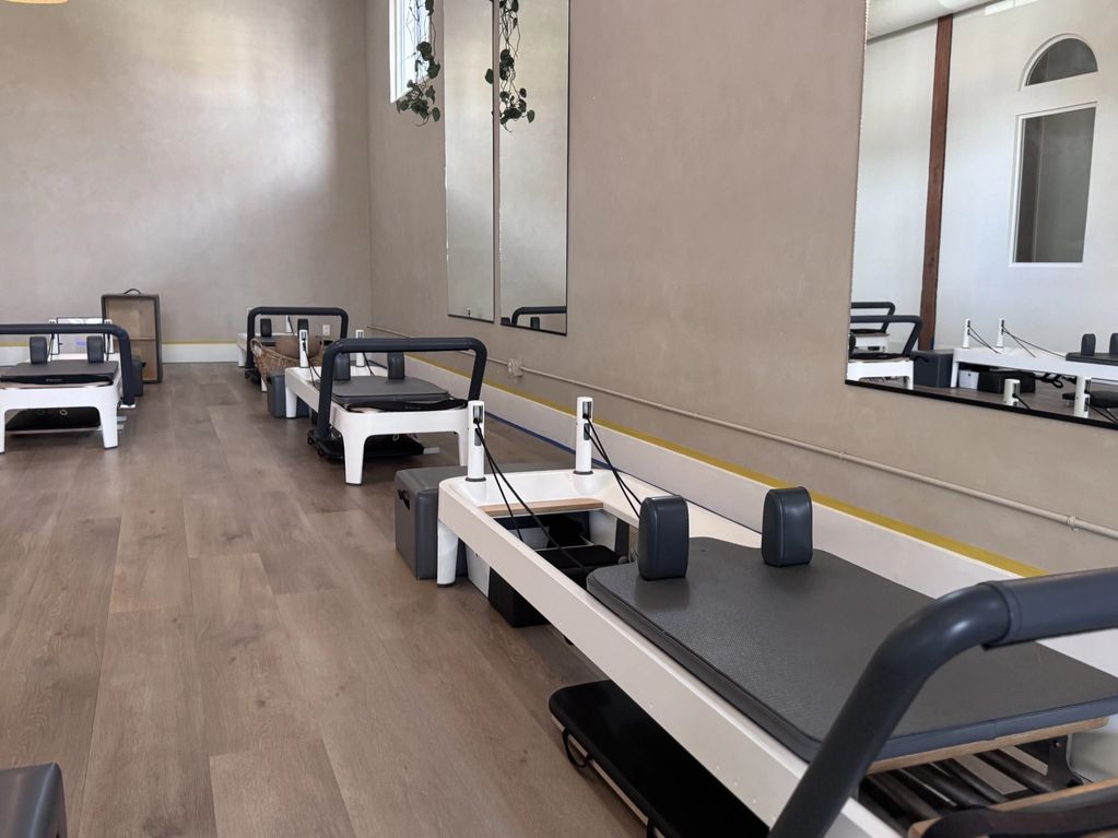 Empty Pilates reformer machines in a fitness studio.