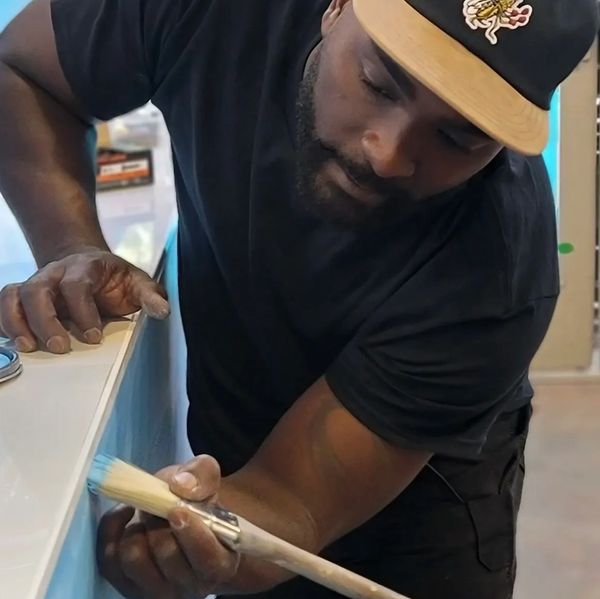 Man carefully painting a surface with a brush.