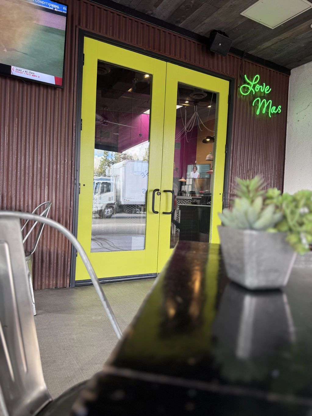 Yellow doors with a green neon sign reading 'Love Mas'.