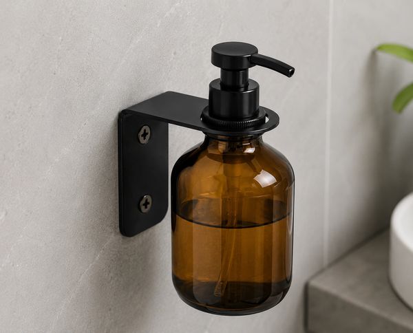Wall-mounted amber soap dispenser with black pump.