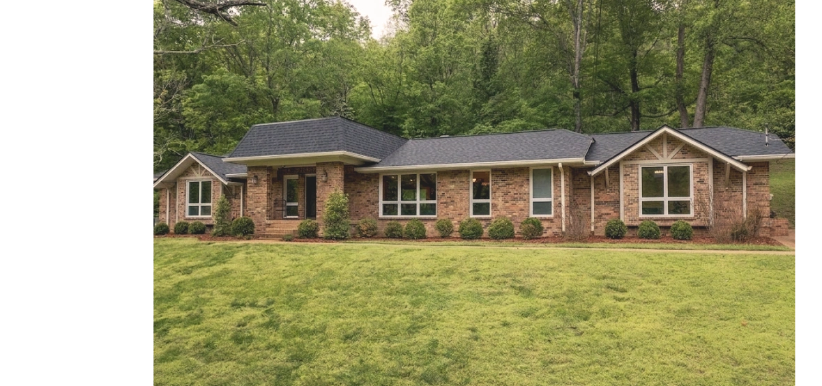 Single-story brick house with large windows and a manicured lawn.