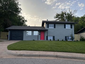 Modern gray house with a bright red door and well-kept lawn.