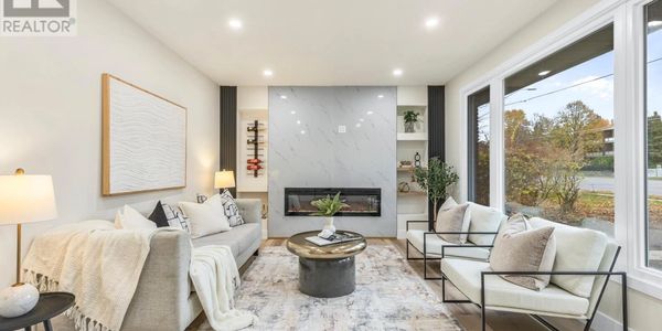 Modern living room with neutral tones and large windows.