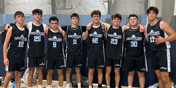 High school basketball team in black uniforms posing together on court.