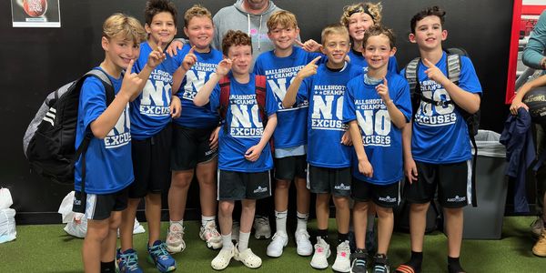 Youth basketball team celebrating a championship win with matching blue shirts.
