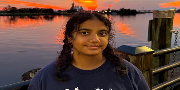 Young woman by waterfront at sunset.
