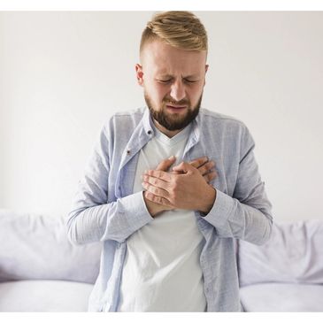Man clutching his chest in pain, possibly experiencing discomfort or heart issues.