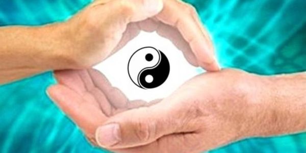 Hands forming a circle around a yin-yang symbol emitting light.