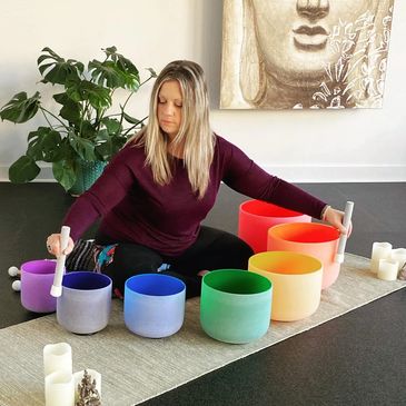 Woman playing colorful singing bowls in a peaceful room.