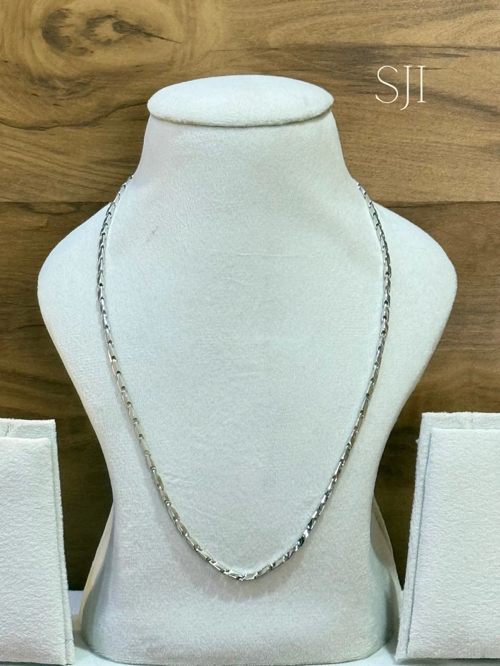 Silver chain displayed on a white stand.