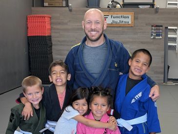 Martial arts instructor with five smiling children in gis.