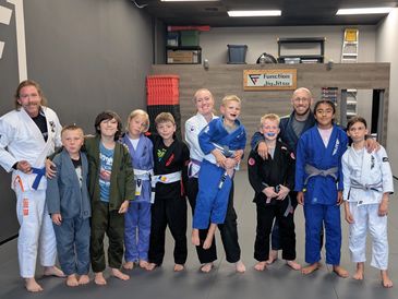 Group of kids and instructors in martial arts uniforms at a dojo.