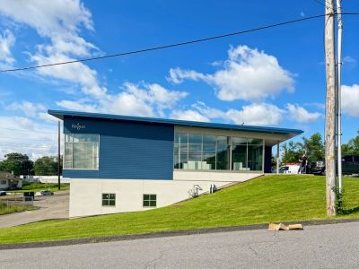Modern blue and white building on a grassy hill under a cloudy sky.