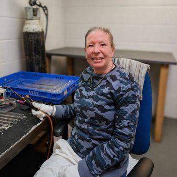 Woman in camouflage shirt working with tools in a workshop.