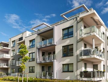 Modern apartment building with balconies under clear blue sky.
