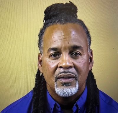 Man with dreadlocks and a goatee, wearing blue.