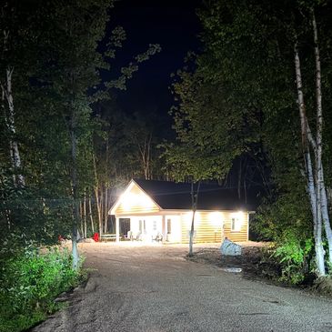 Maison éclairée la nuit au milieu des arbres.