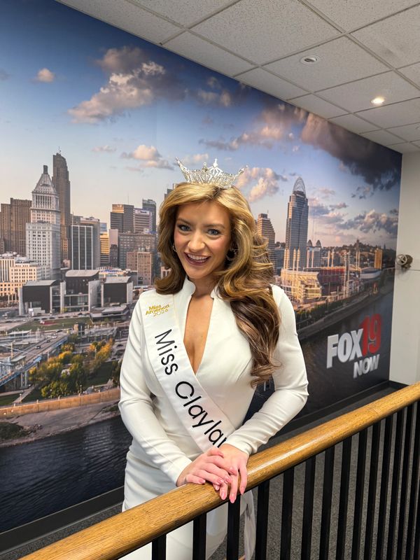 Miss Clayland 2023 wearing a crown and white dress, smiling indoors.