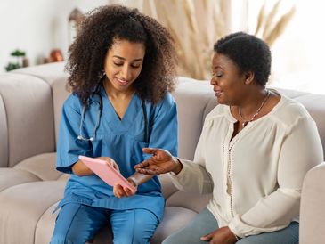 A nurse offering companionship to a patient at home