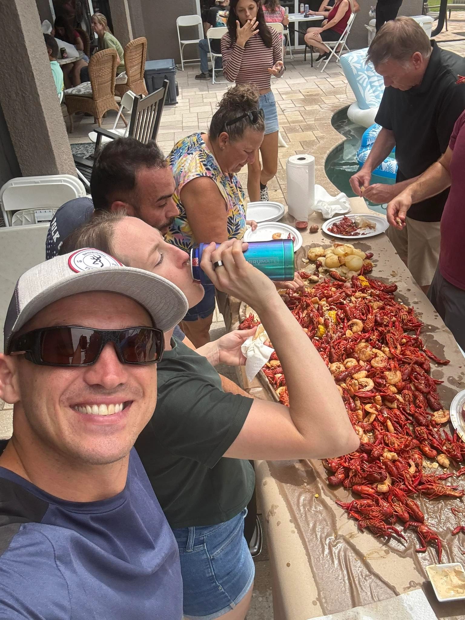 A group of people at a table eating boiled crawfish and shrimp enjoying themselves.