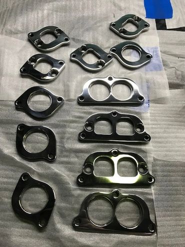 Various metallic automotive gaskets arranged on a surface.