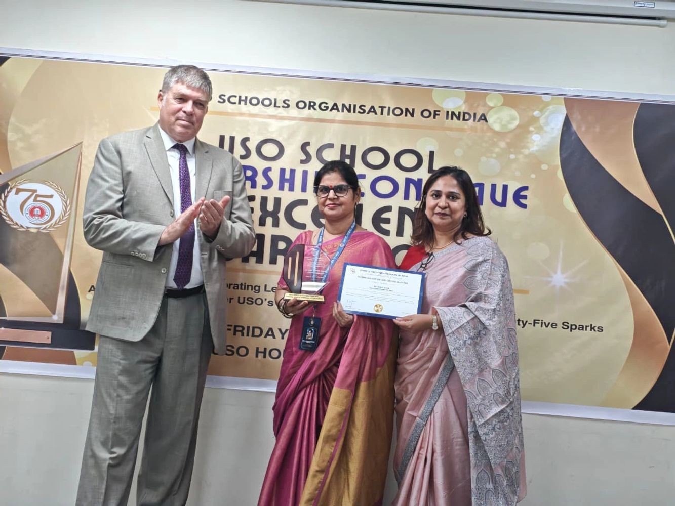 Three people at an award ceremony with a trophy and certificate.