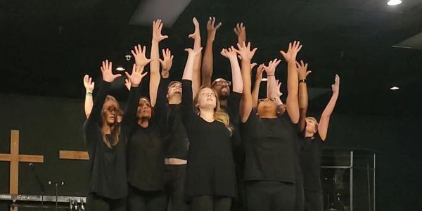 Group of people raising hands on stage.